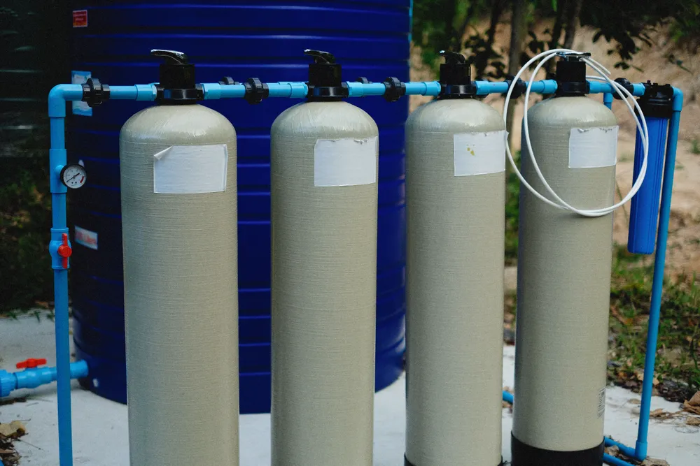 Whole-house water treatment tanks with blue supply piping — illustrative photo of a residential softener/filtration setup, not an installation by this site